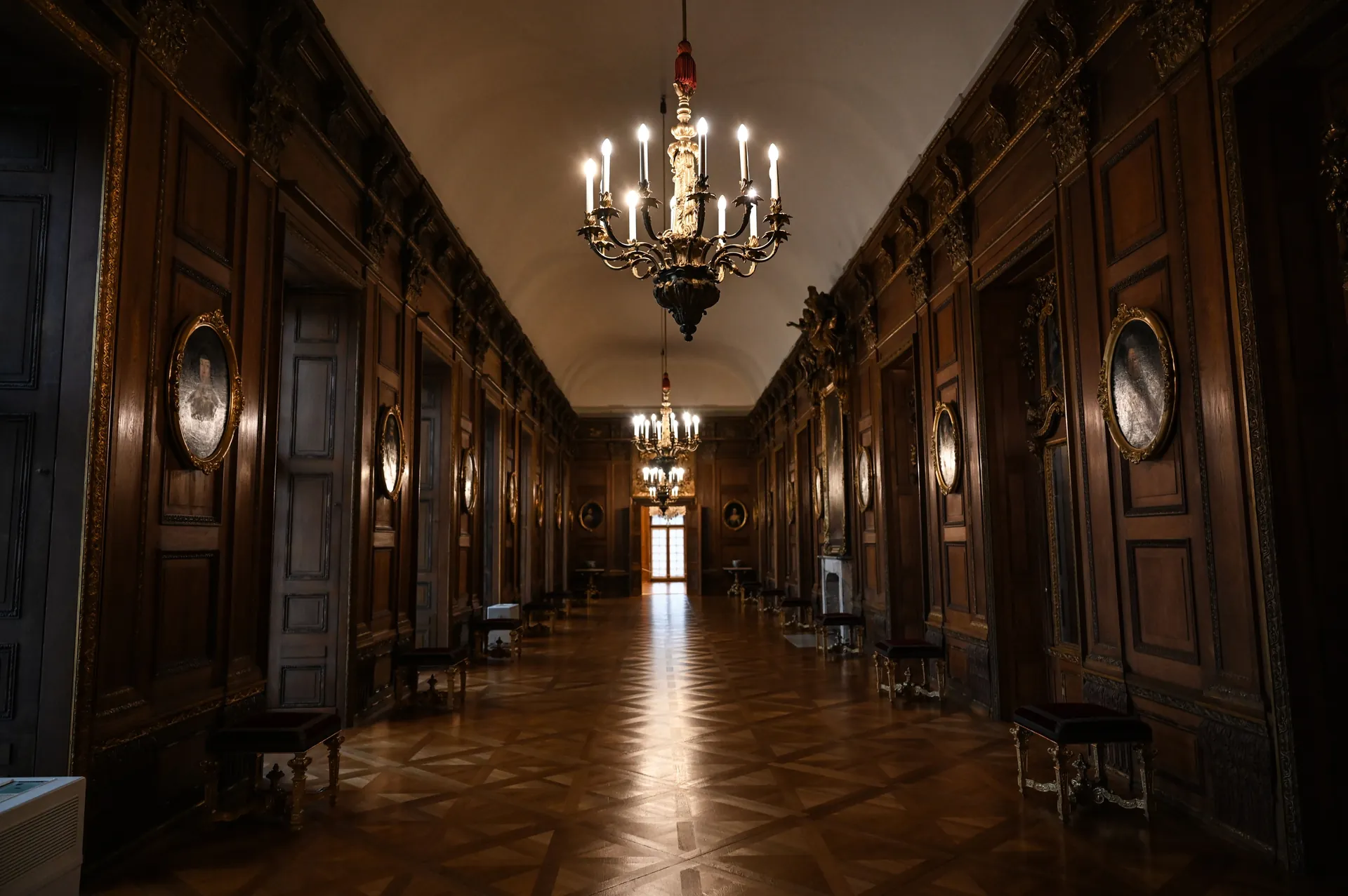 Long wood-panelled corridor with chandeliers